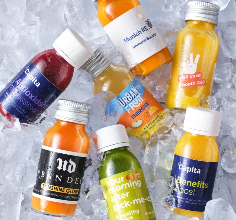 Several bottles of branded juice lying on top of a bed of ice