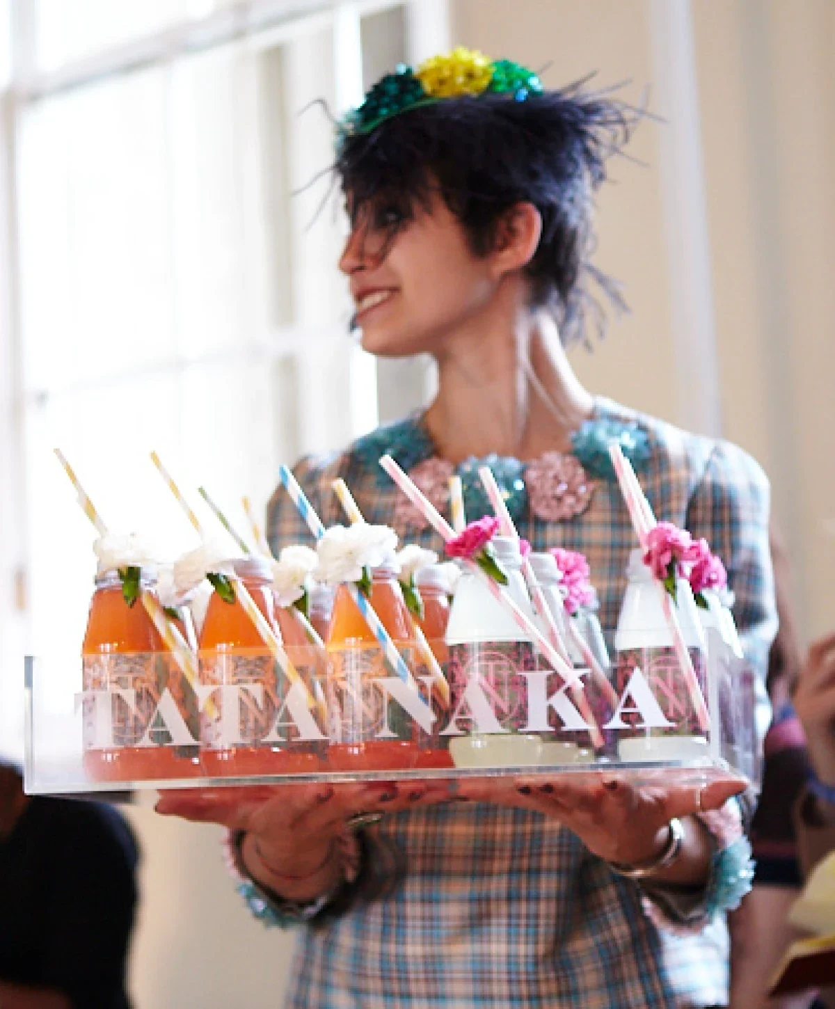 A tray full of branded juice bottles being carried by a woman