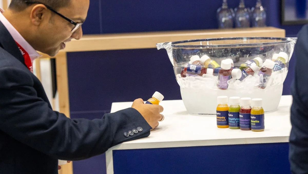 A man at an exhibition inspecting a bottle of juice shot