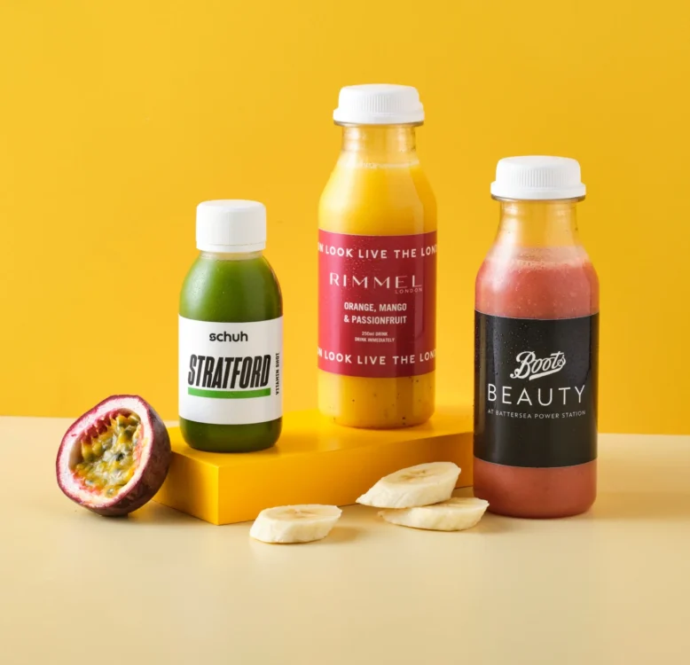 Three bottles of custom branded juice with the ingredients next to the bottles