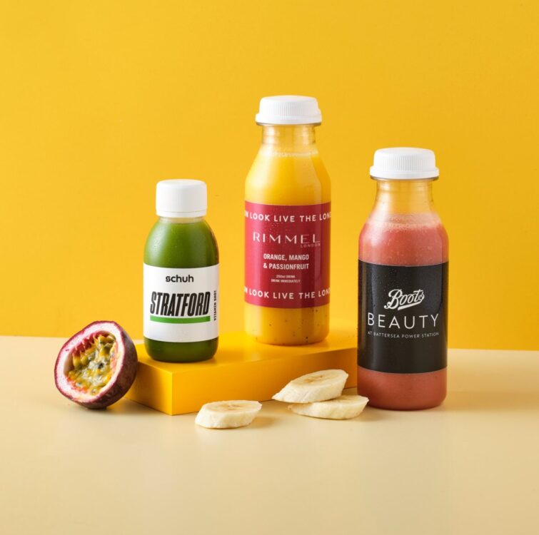 Two bottles of smoothie and a juice shot on a yellow background