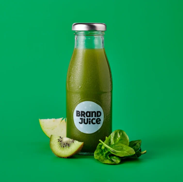 a bottle of green juice with a clear label on a green background with ingredients next to the bottle