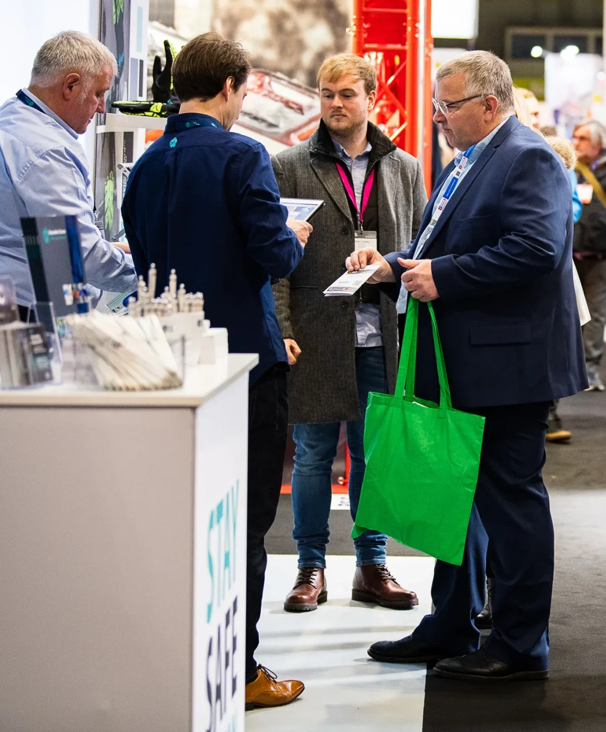 A group of business people talking at an exhibition and holding branded drinks