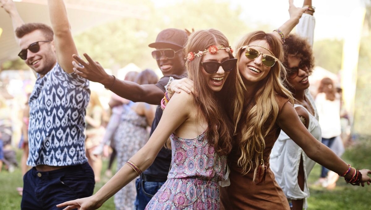 Two women dancing at a music festival with other people dancing in the background