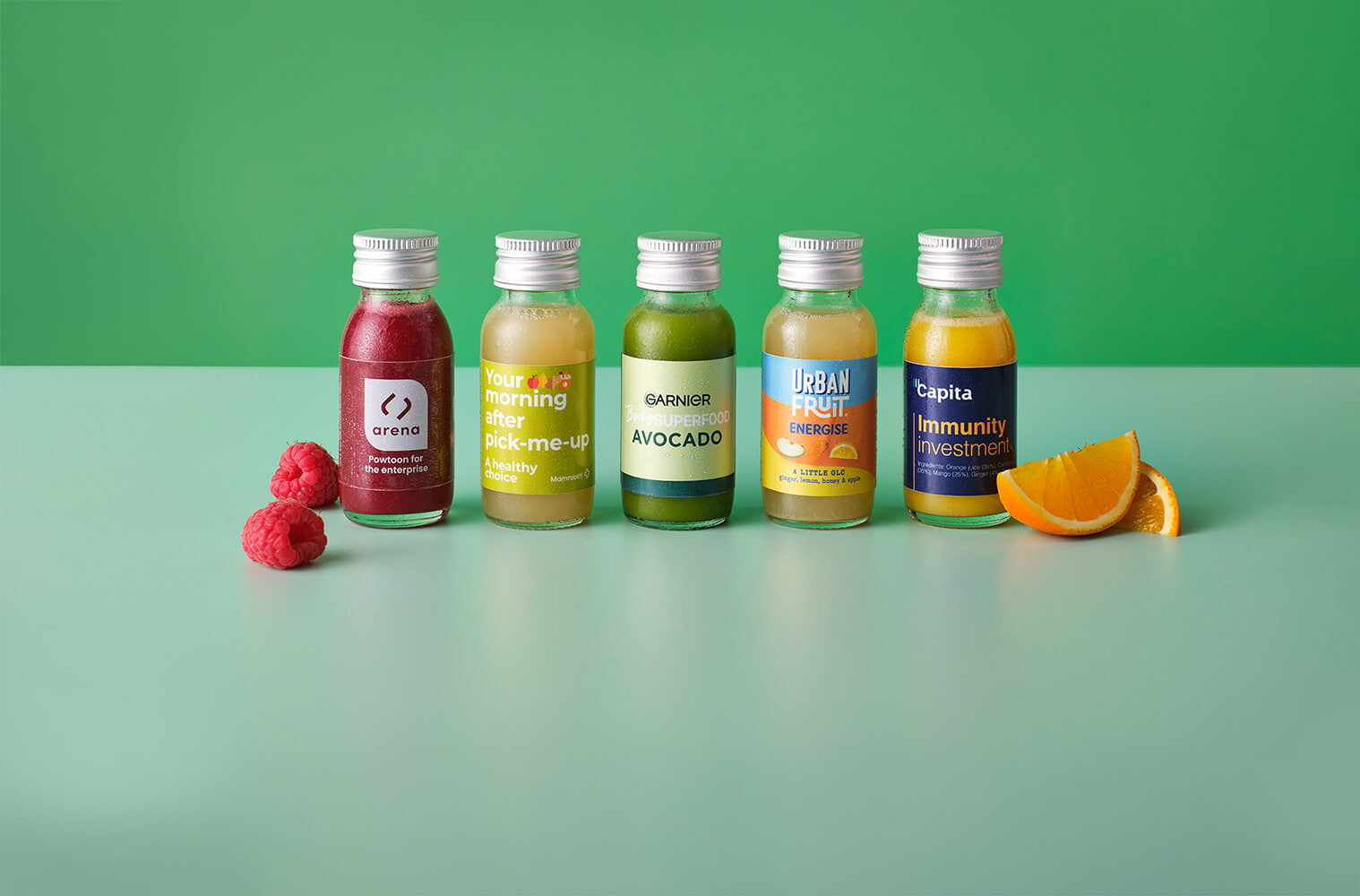 Five juice shots lined up against a green background